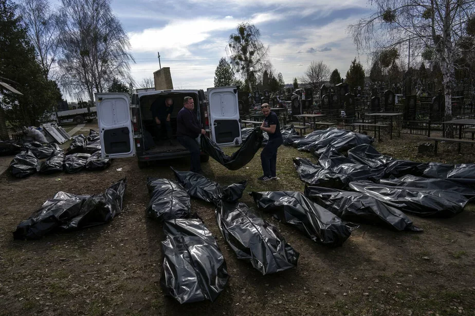 Работнікі могілак выгружаюць целы загінулых мірных жыхароў на могілках у Бучы, 7 красавіка 2022 г. Фота: Rodrigo Abd / AP