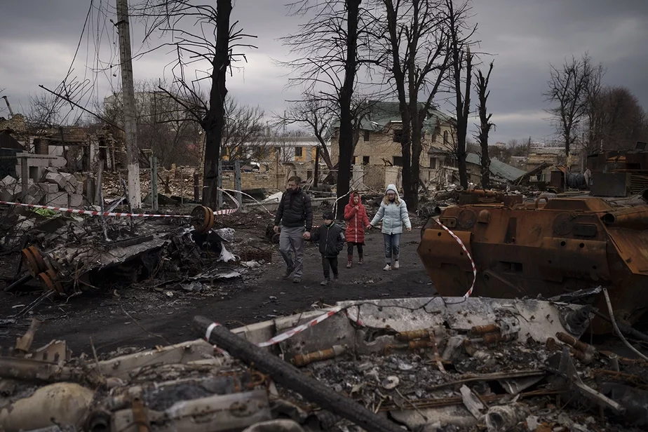 Семья идет по разрушенной улице в Буче, где стоят уничтоженные российские танки. Украина, 6 апреля. Фото: Felipe Dana, AP Photo